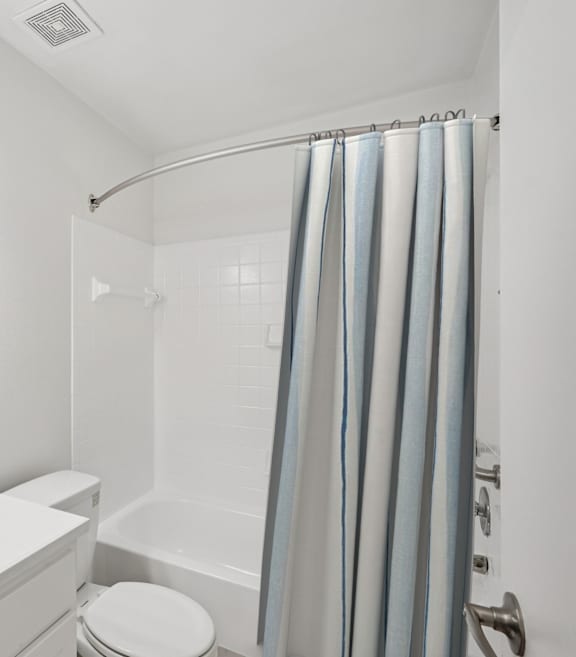 A white bathroom with a toilet, sink, and shower.