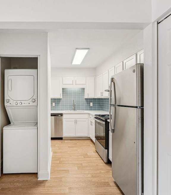 A white kitchen with a refrigerator, dishwasher, and oven.