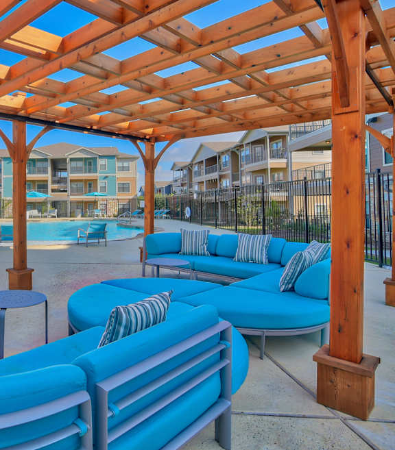 A wooden pergola over a blue seating area.