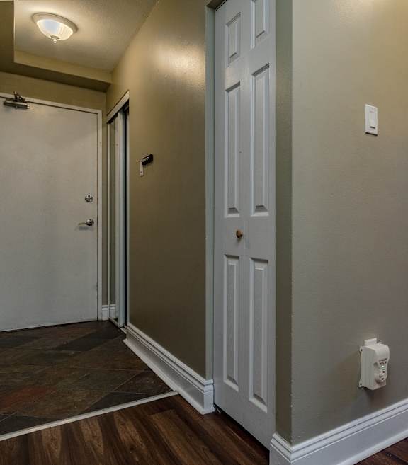 A hallway with a white door and a white light switch on the wall.
