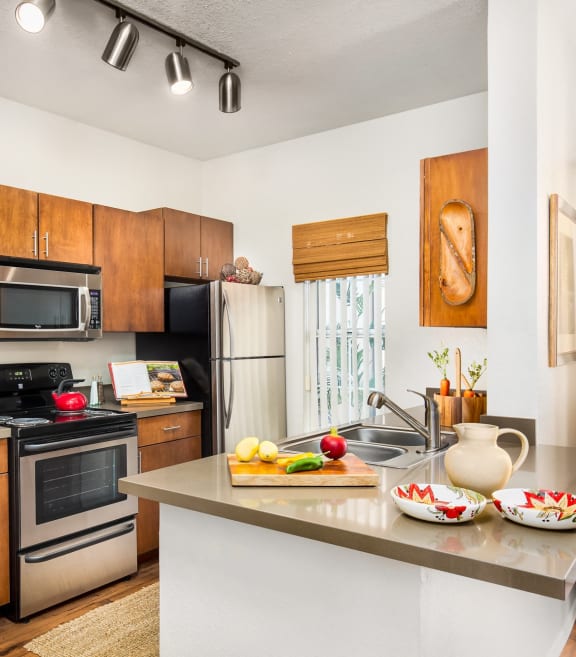 full kitchen with stainless steel appliances and wooden cabinets and a island with food on it