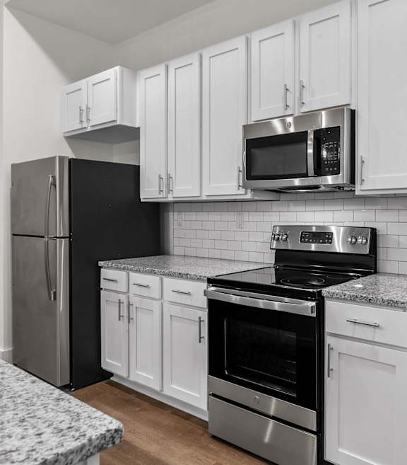 A kitchen with white cabinets and black appliances. at The Quarter Lofts Apartments, Mississippi, 39216