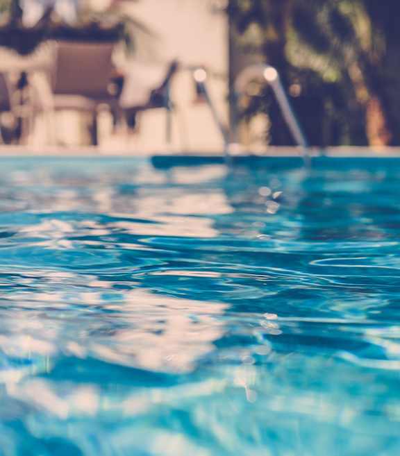 A pool with clear blue water and sunlight reflecting off the surface.