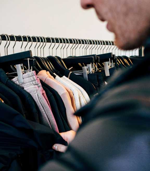 A man is looking at clothes on a rack.