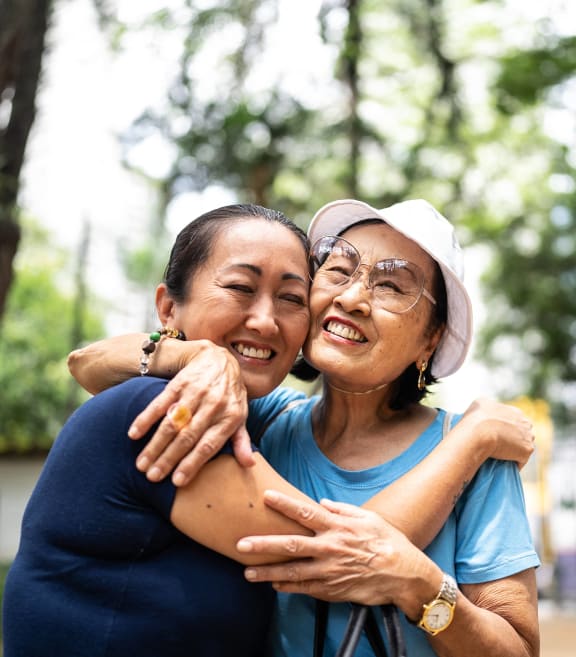 two women hugging each other with trees in the background