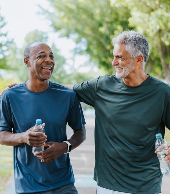 two men walking in the park holding bottles of water