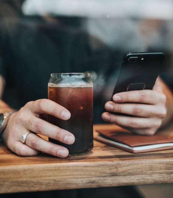 a woman sitting at a table with a cup of coffee and her phone