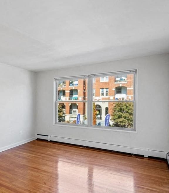 an empty living room with a large window and wooden floors