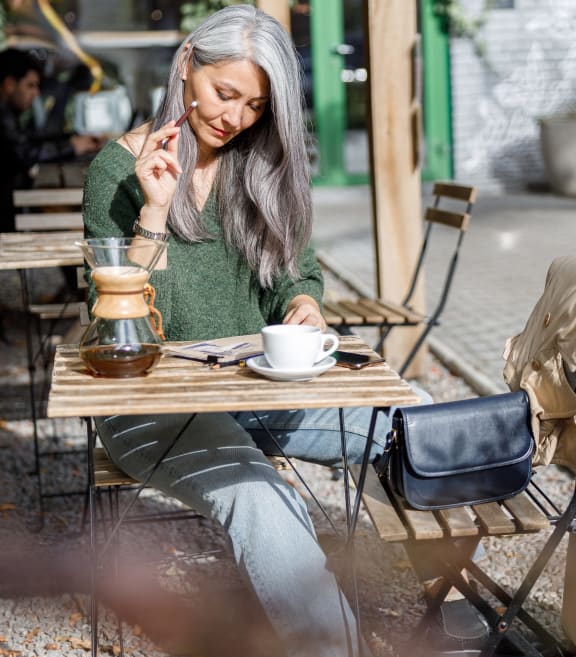 a woman sitting at a table with a cup of coffee at The James at Chatham Hills, Westfield, IN