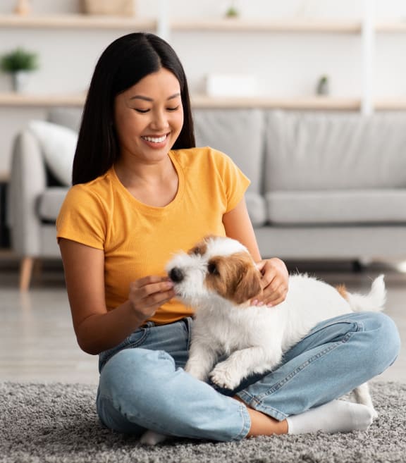 a woman sitting on the floor petting a small dog at The James at Chatham Hills, Westfield, IN