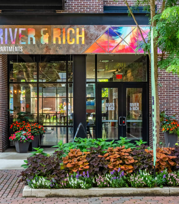 a brick building with a large glass door and colorful paintings on the wall