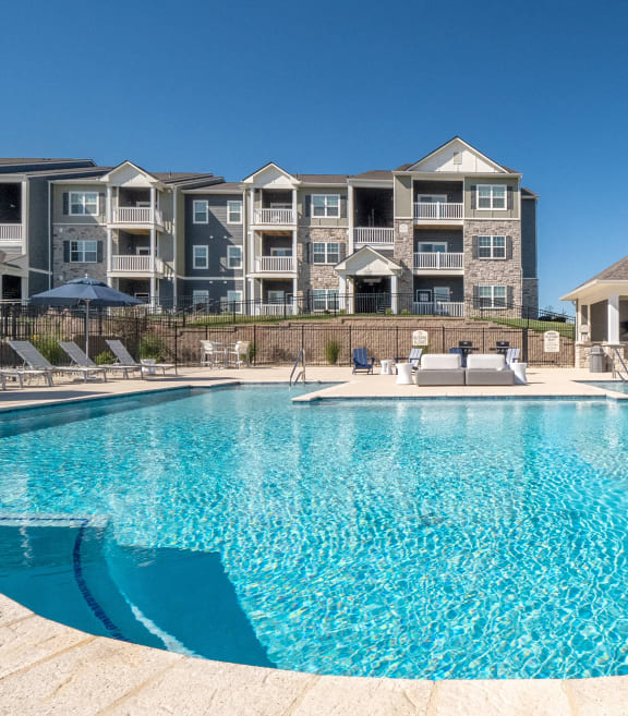 a patio with tables and chairs at the whispering winds apartments in pearland, tx
