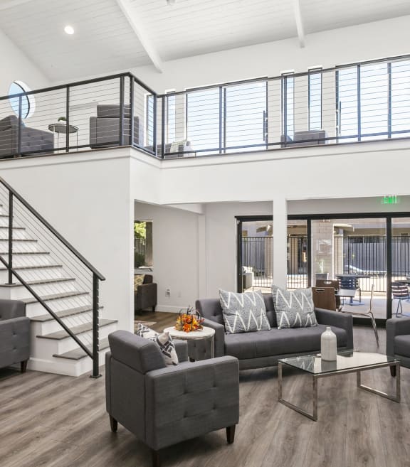 a living room with couches and chairs and a staircase