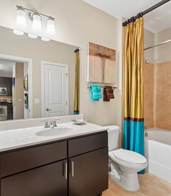 A bathroom with a white sink and brown cabinets.