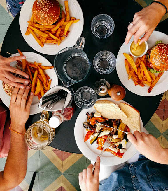 A top view of a group of people sharing a meal with burgers and fries.