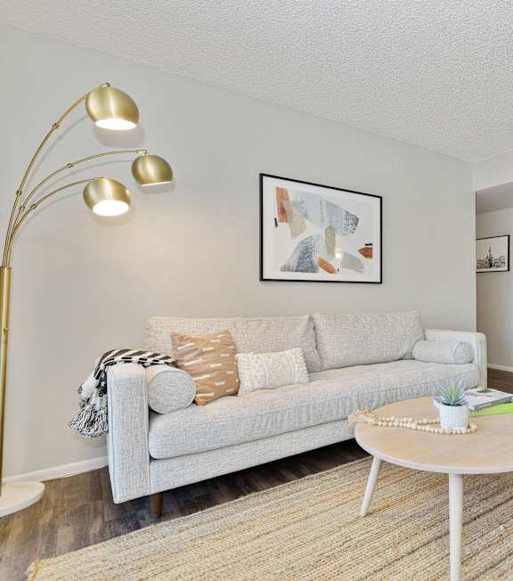 A living room with a white couch, a coffee table, and a floor lamp.