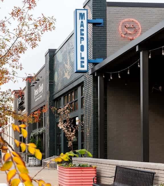 A restaurant named Mae's is shown with a neon sign and outdoor seating.