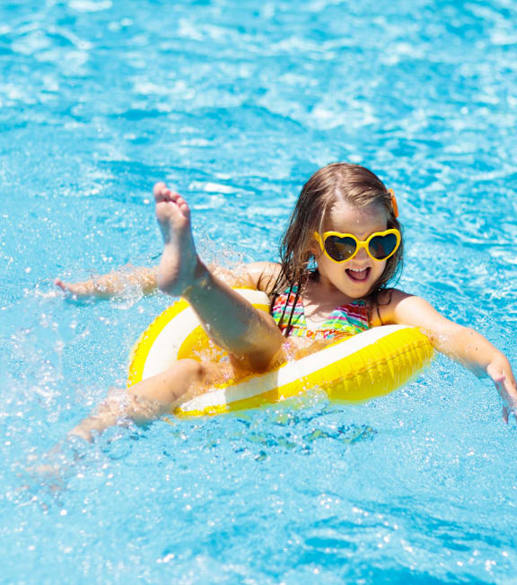 A girl in a swimming pool wearing sunglasses and a bikini.
