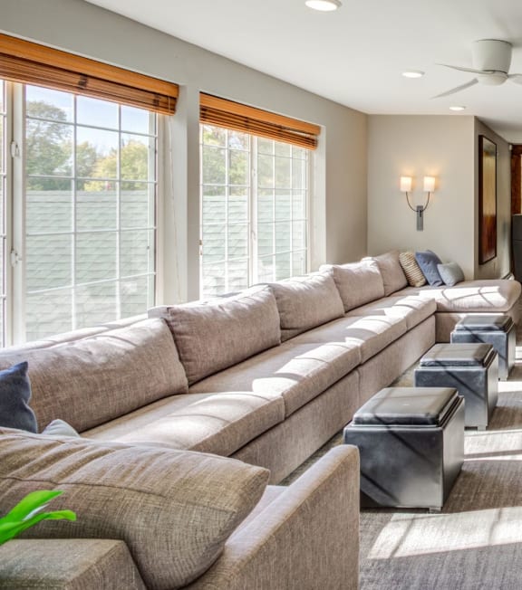 a living room with couches and chairs and large windows