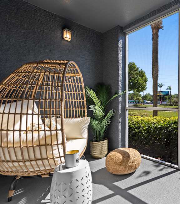 A patio with a chair and a table with a hat on it.