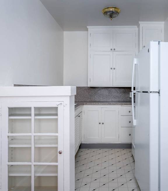A kitchen with white cabinets and a white refrigerator.