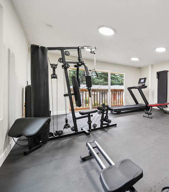 A spacious home gym with a variety of equipment including a treadmill, weights, and a bench press.