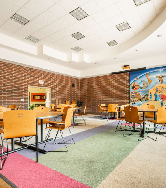 a large room with tables and chairs and a mural on the wall