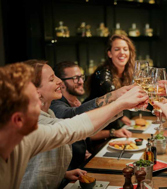 A group of people toasting with glasses of wine at a dinner table.