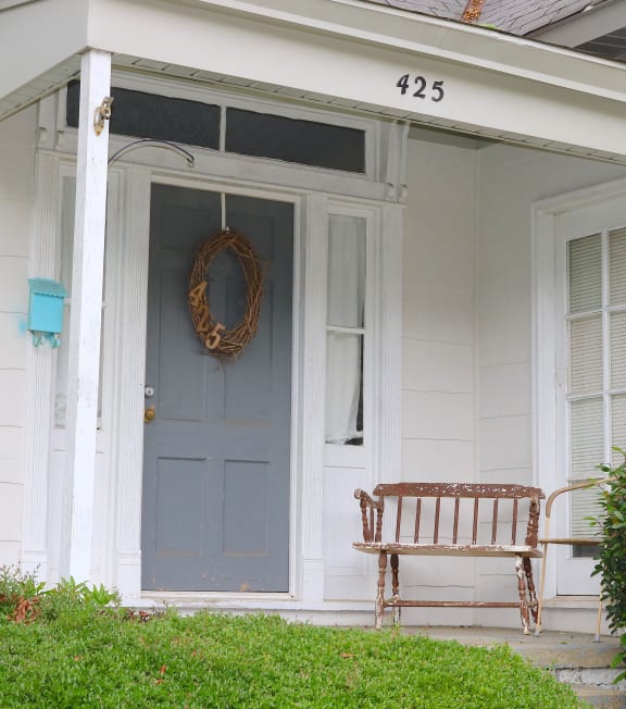 a front porch with a bench and a blue door
