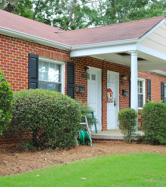the front of a brick house with a porch and a lawn