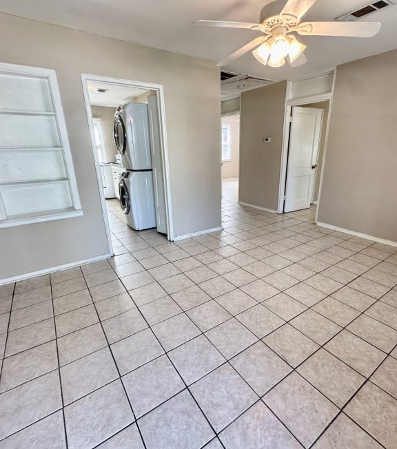 an empty living room with tile flooring and a ceiling fan