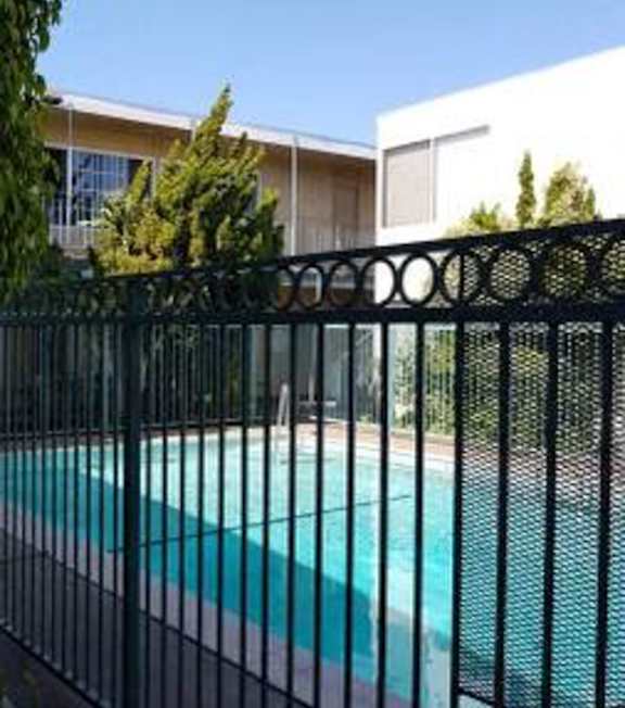 A pool with a hot tub and lounge chairs in front of a building.