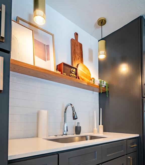 a kitchen with black cabinets and white counter top and a sink