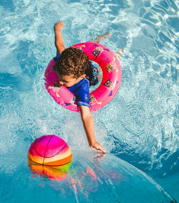 A child is playing with a ball in a pool.