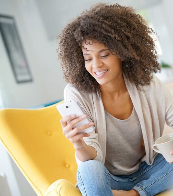 a woman sitting on a chair drinking coffee and looking at her cell phone at The Rail, St. Louis, MO