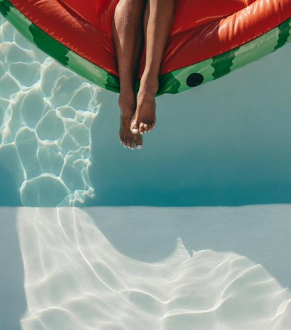 A person is floating on a red and green inflatable in the water.