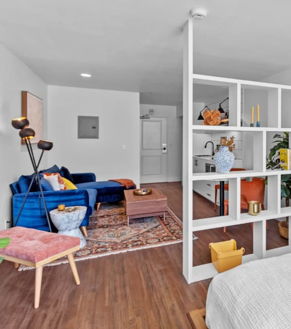 A living room with a blue sofa and a white shelving unit.