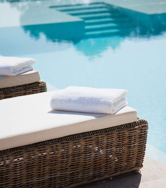 Towels on a wicker chair by a pool