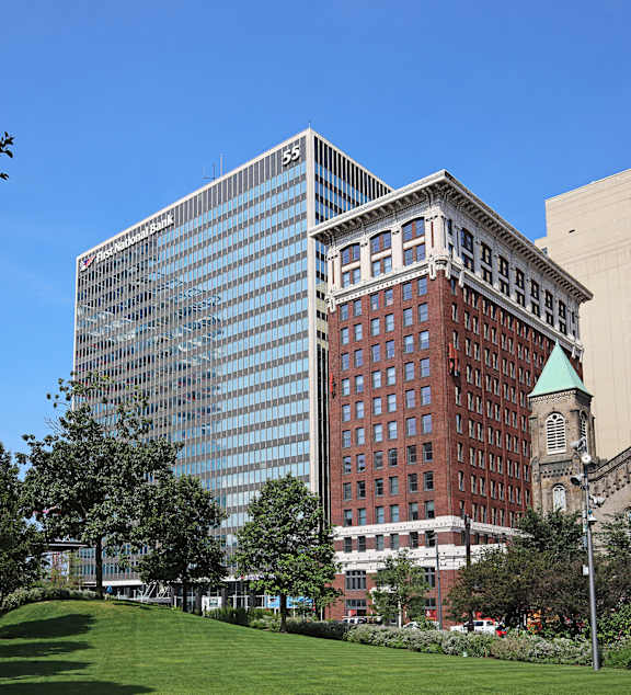 A large glass building with the number 55 on it is in the background of a city scene.