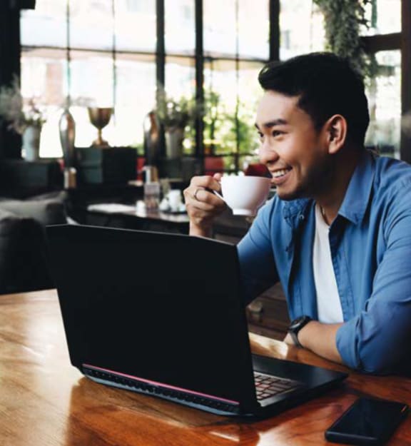 Man Working On His Laptop While Having A Coffee at Trelago Apartments, Maitland, Florida