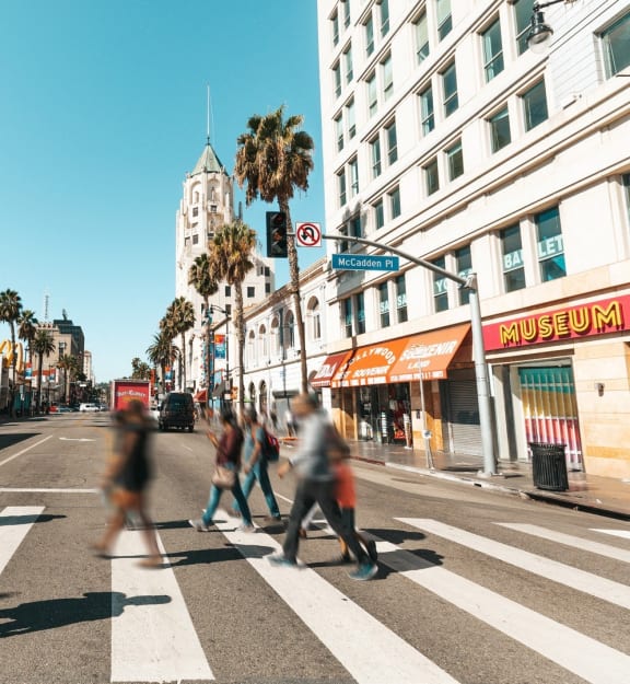 people crossing the street at a crosswalk in a busy city