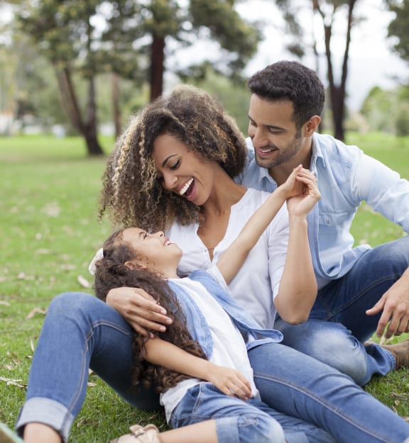 a man and woman sitting on the grass with a child
