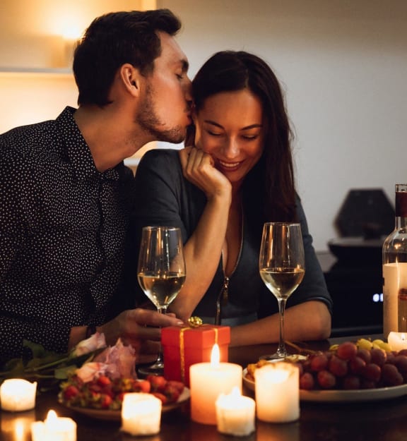 a couple kissing at a table with wine and candles