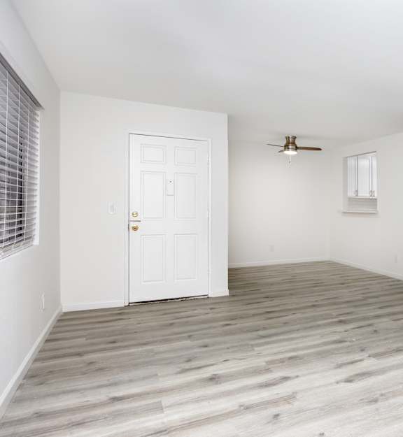 an empty living room with wood floors and white walls
