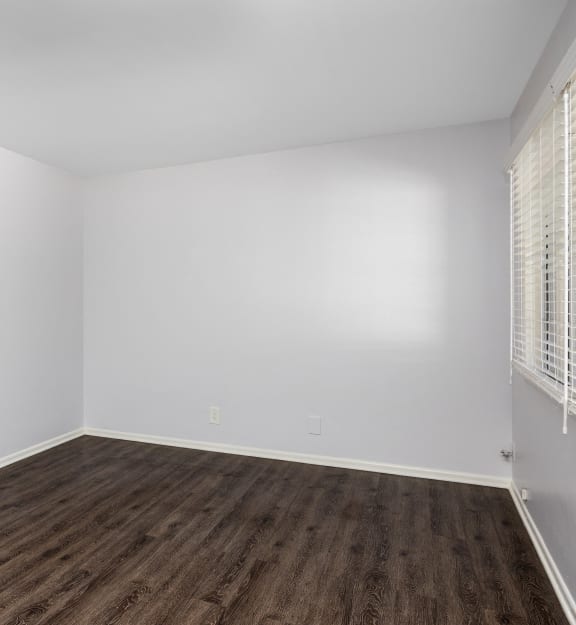 an empty room with wood floors and white walls