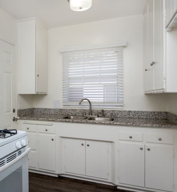 a kitchen with white appliances and granite counter tops and white cabinets