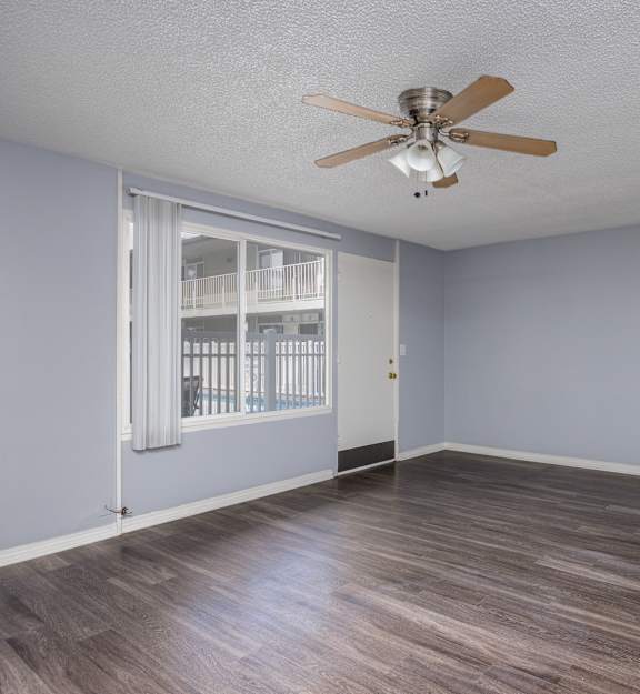 A room with a ceiling fan and wooden flooring.