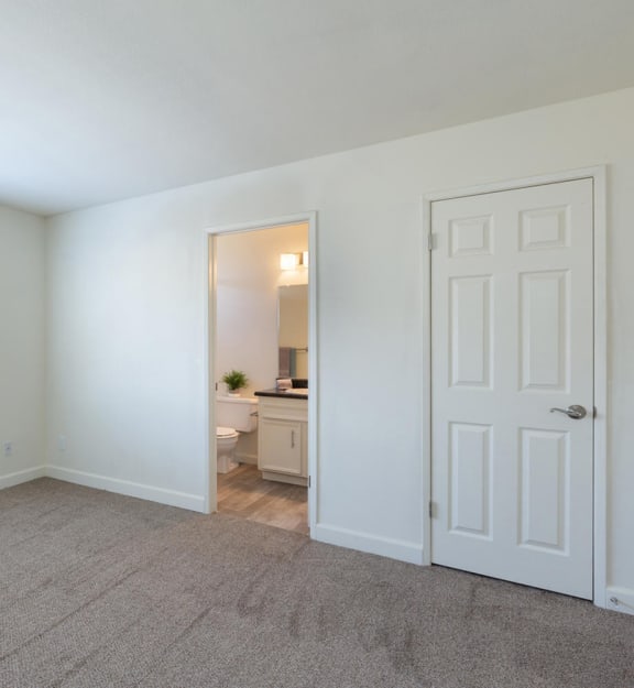 a bedroom with a large window and a door to a bathroom