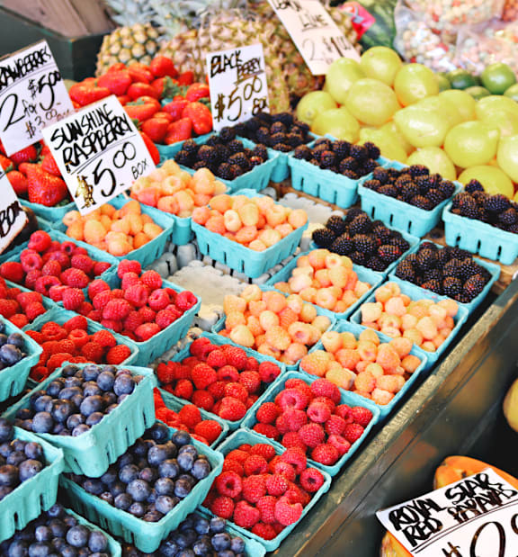 A fruit stand with a variety of fruits including blueberries, raspberries, and pineapples.