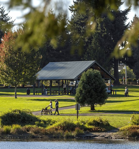 A family is walking in a park with a pavilion in the background.